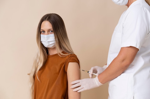 Foto mujer con máscara médica recibiendo una vacuna