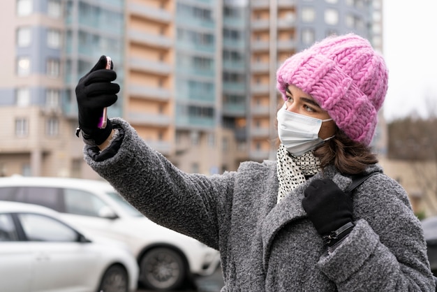 Mujer con máscara médica tomando un selfie en la ciudad