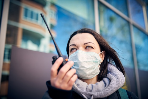 Mujer con máscara médica transmitida por radio portátil profesional