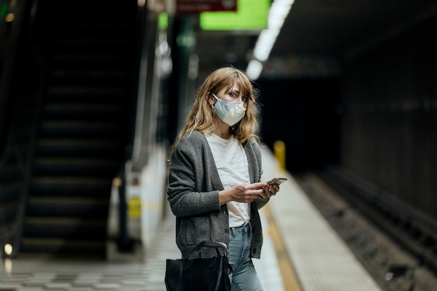 Mujer con máscara mientras espera el tren durante la pandemia de coronavirus