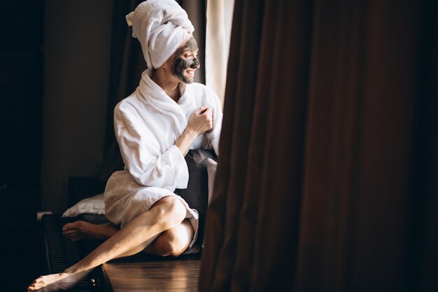 Mujer con máscara negra en la cara en bata de baño