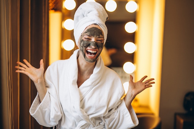 Mujer con máscara negra en la cara en bata de baño