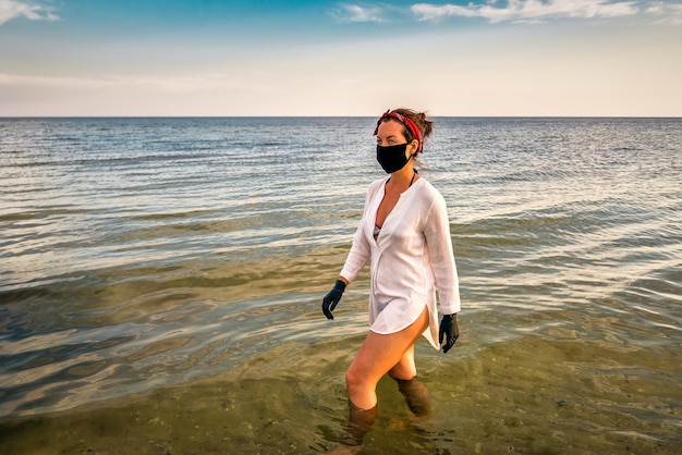 Mujer con máscara negra y guantes en el mar.