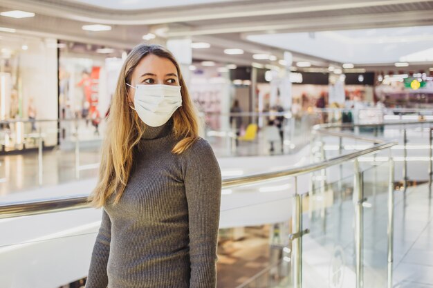 Foto mujer con máscara de pie en el centro comercial