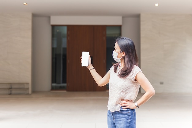 Mujer con máscara protectora haciendo videollamadas en el teléfono celular.