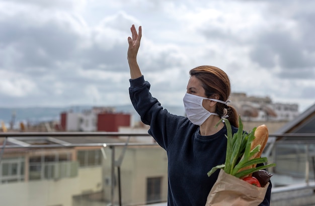 Foto mujer con máscara protectora llegando a casa con la compra