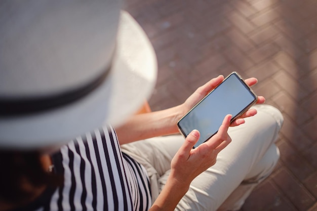 Una mujer con una máscara protectora mira la pantalla de su teléfono inteligente