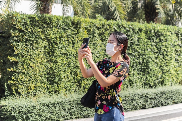 Mujer con máscara protectora tomando fotografías con su teléfono celular.