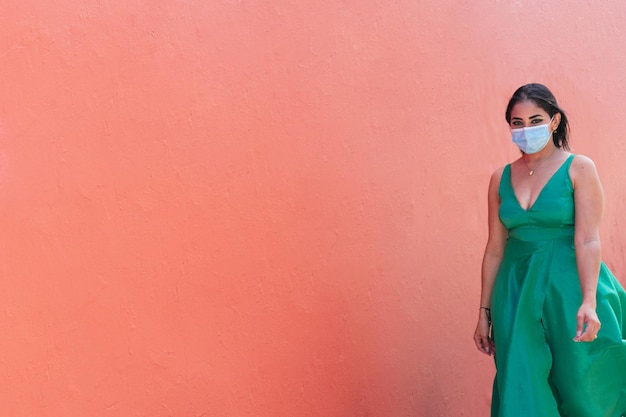 Mujer con máscara protectora y vestido verde caminando por la calle