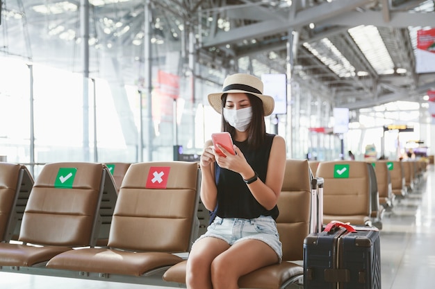 Mujer con máscara usando un teléfono en un aeropuerto