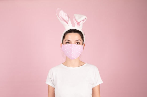 Mujer con mascarilla con una diadema de orejas de conejo de pascua. Pascua durante la cuarentena por coronavirus