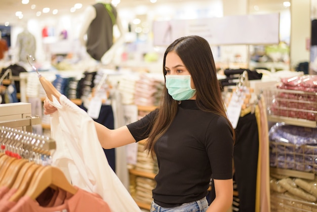 Mujer con mascarilla es comprar ropa en el centro comercial