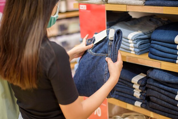 Mujer con mascarilla es comprar ropa en el centro comercial