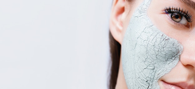 Mujer con mascarilla facial de arcilla para el cuidado de la piel.