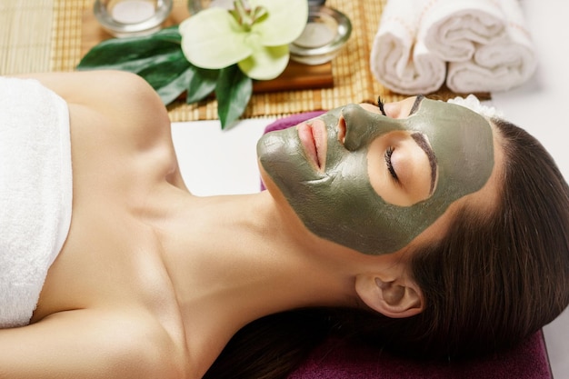 Mujer con mascarilla facial de arcilla en el spa de belleza Concepto de belleza para el cuidado de la piel