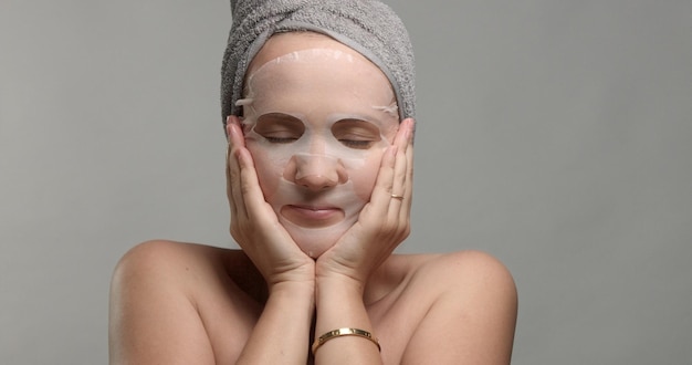 Una mujer con una mascarilla facial se hace un masaje facial