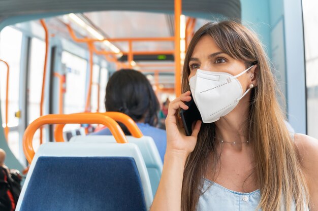 Mujer con mascarilla hablando por teléfono a bordo del tren.