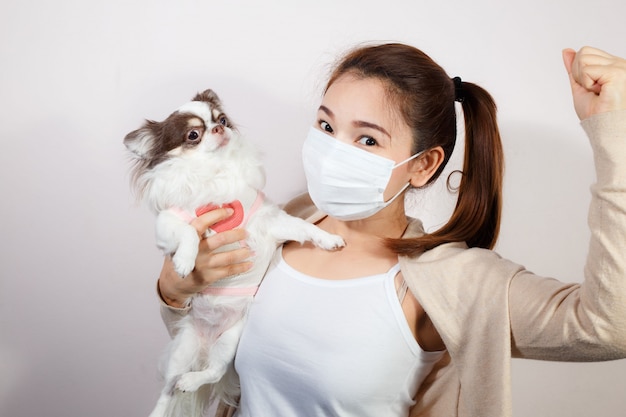 Mujer con mascarilla y hoding un perro