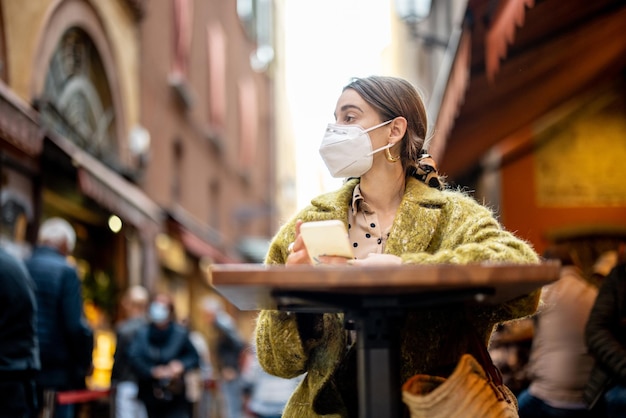 Mujer con mascarilla médica en un restaurante al aire libre