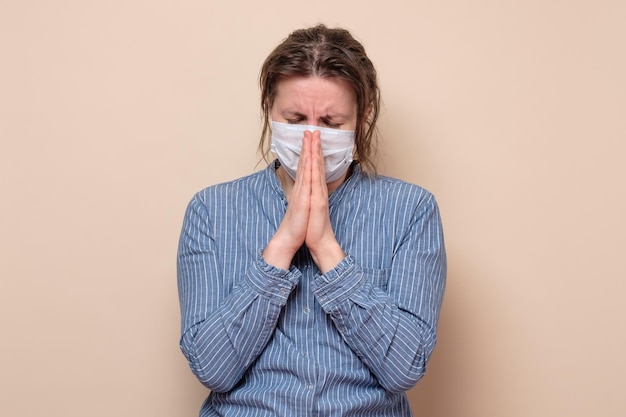 Mujer con mascarilla médica rezando por la ayuda de Dios durante la pandemia del coronavirus