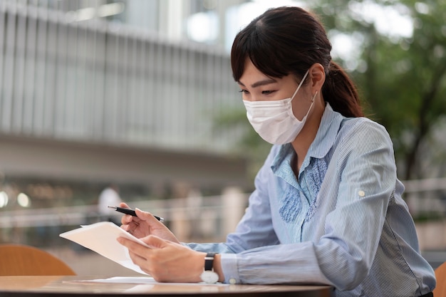 Foto mujer con mascarilla en la mesa