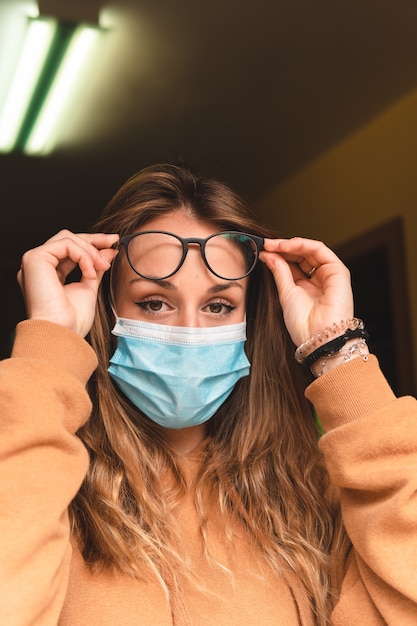 Foto mujer con mascarilla mirando por la ventana