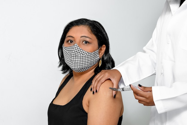 Foto mujer con mascarilla protectora recibe un disparo en el brazo de un trabajador de la salud