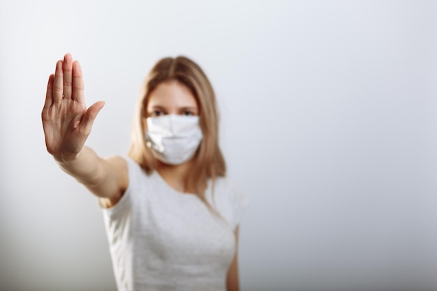 Mujer con mascarilla que muestra la señal de alto con la mano para evitar la propagación de los virus Enfoque selectivo