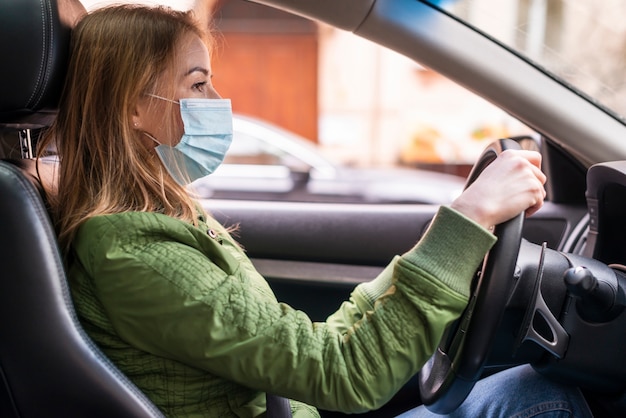 Mujer con mascarilla quirúrgica en el coche