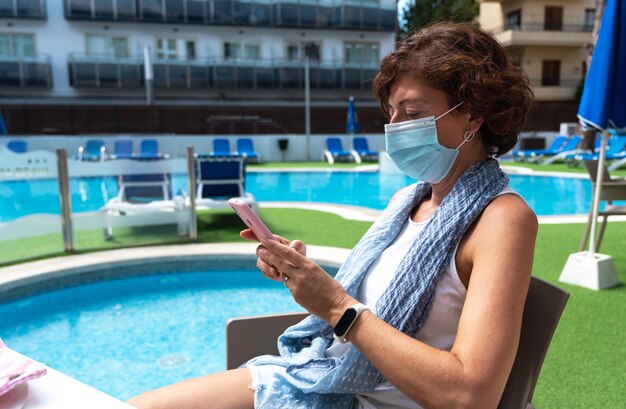 Foto mujer con mascarilla quirúrgica consultando su móvil