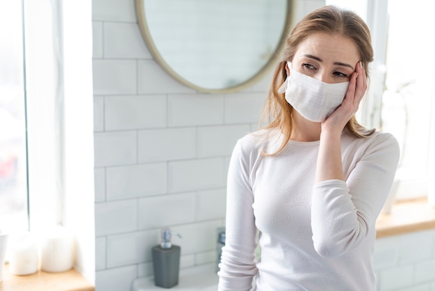 Foto mujer con mascarilla quirúrgica que tiene dolores de cabeza