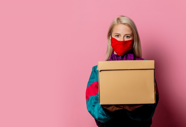 Mujer en mascarilla y ropa de los 80 con caja de entrega en rosa