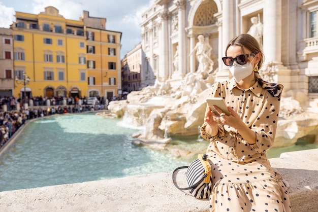 Mujer con mascarilla visitando la famosa fuente di Trevi en Roma