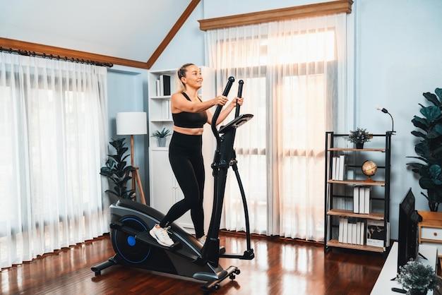 Mujer mayor activa corriendo en una máquina elíptica en casa retrato en foto de cuerpo completo como estilo de vida saludable y cuidado del cuerpo después de la jubilación para el pensionista Clout