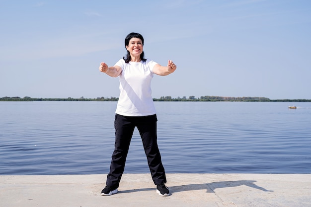 Mujer mayor activa y feliz haciendo ejercicio cerca de la orilla del río