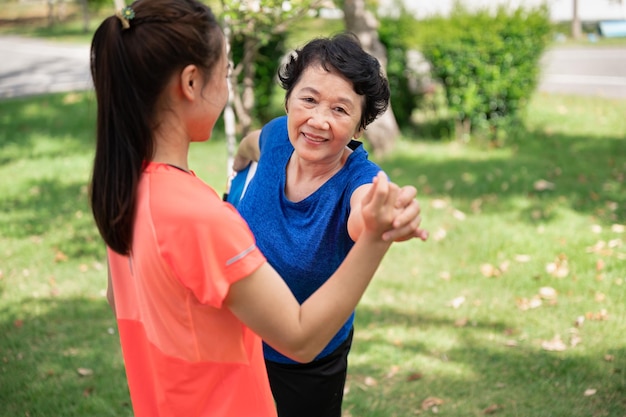 Mujer mayor y adolescente de Asia entrenando yoga en el jardín