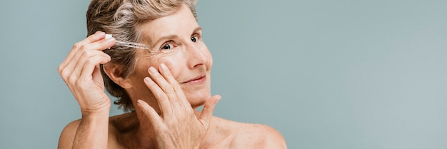 Foto mujer mayor aplicar crema hidratante en las arrugas de sus ojos