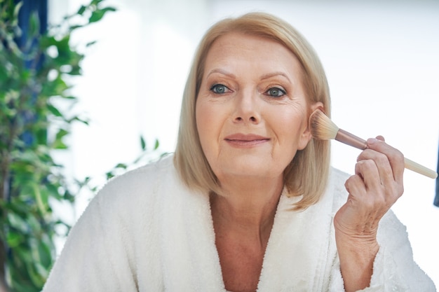 mujer mayor, aplicar maquillaje, en el baño