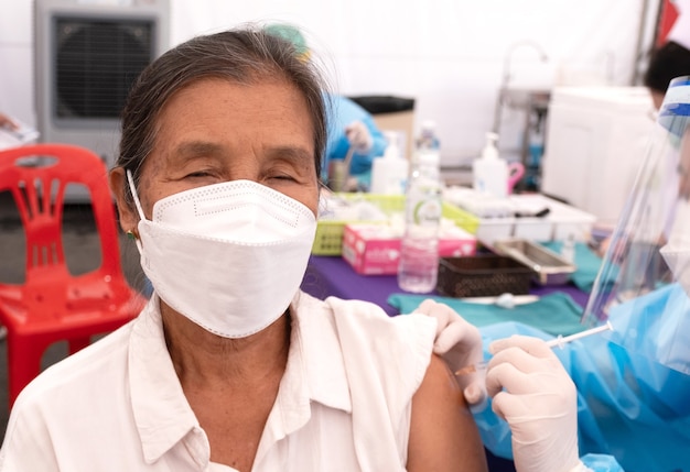 Mujer mayor de Asia ha ido a vacunar el coronavirus covid19 con personal médico en un hospital de campo