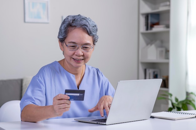 Mujer mayor asiática que usa Laptop y pago con tarjeta de crédito para comprar en línea con conexión de red de clientes a través del sistema omnichannel Mujer mayor con tecnología