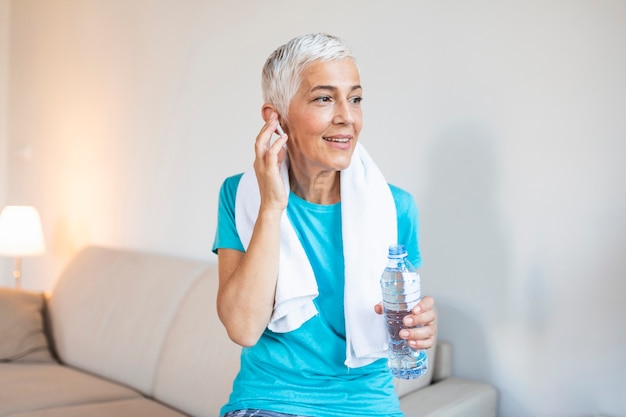 Mujer mayor con auriculares mientras descansa después del entrenamiento