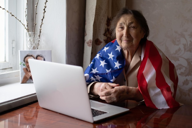 Mujer mayor con bandera americana sentada en casa.