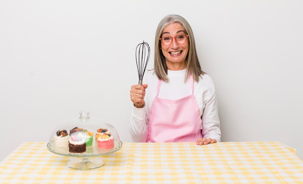 Mujer mayor de cabello gris que parece feliz y gratamente sorprendida concepto de pasteles caseros