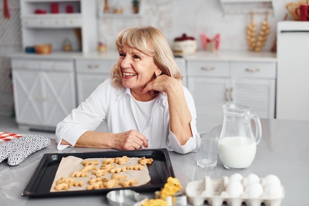 Mujer mayor cocina galletas de Navidad en la cocina durante el día