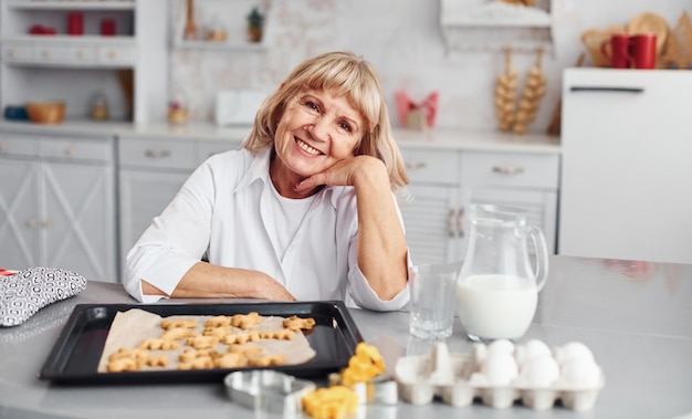 Mujer mayor cocina galletas de Navidad en la cocina durante el día