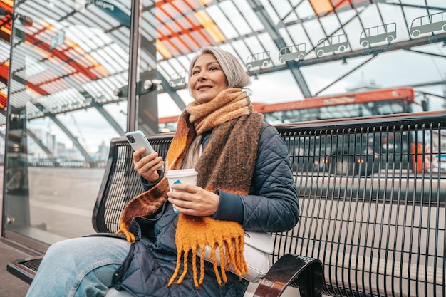 Mujer mayor compra el billete de tren con el teléfono inteligente