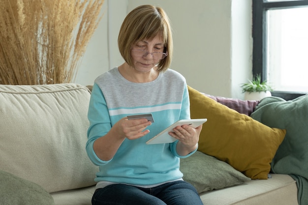 Mujer mayor de compras en línea con tarjeta de crédito mediante tableta digital