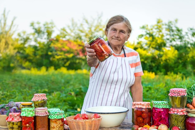 Mujer mayor conservando verduras en frascos Enfoque selectivo