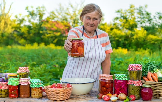 Mujer mayor conservando verduras en frascos Enfoque selectivo