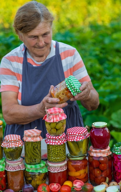 Mujer mayor conservando verduras en frascos Enfoque selectivo